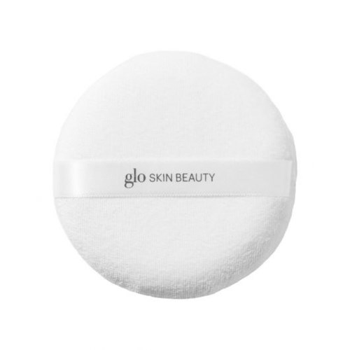 A round white item with the words "glo SKIN BEAUTY" written across it, looks like a cosmetic product.