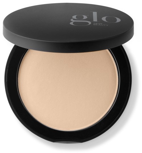 A compact powder case with a beige pressed powder and a black lid with white text.