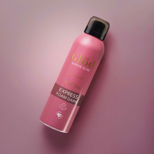 Eine rosa Flasche von Glöd Sophie Elise Foam Dark Spray auf rosa Hintergrund.