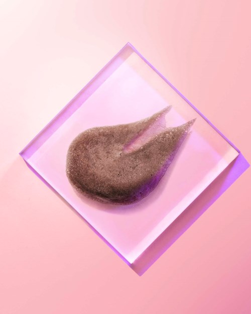 A brown, fuzzy object on a square glass or acrylic stand, with purple and pink lighting effects.