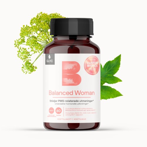 A dark bottle with a label says Balanced Woman and contains supplements for hormonal health. It is surrounded by green leaves.