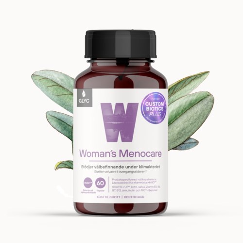 En flaska Woman's Menocare-tillskott med gröna blad i bakgrunden.
