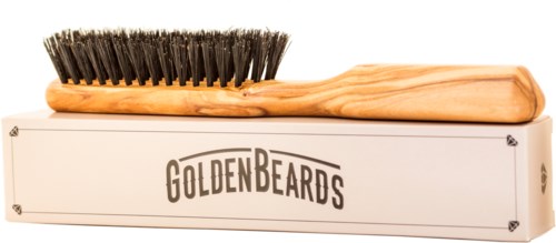 A wooden brush with dark bristles resting on a box labeled 'GOLDEN BEARDS.'