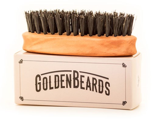 A shoe brush with black bristles sits on a box labeled 'GOLDEN BEARDS'.