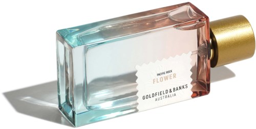 A glass perfume bottle with pastel colors and a gold cap, lying on a white surface with a shadow.