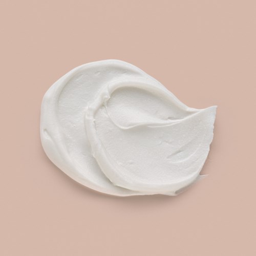 Two dollops of white cream or lotion on a pink background.