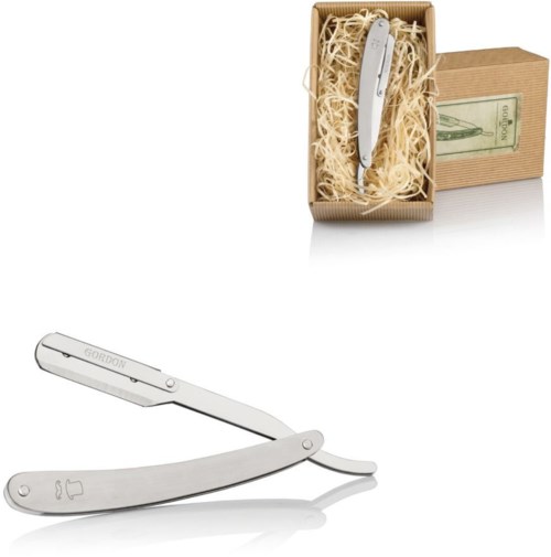 A silver knife with the name 'Gordon' on it, placed in a gift box with shredded paper and a dollar bill.