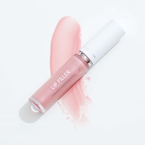 Eine transparente Lipgloss-Flasche mit 'Lip Filler'-Aufdruck liegt auf heller Oberfläche, daneben ist rosa Glanz.