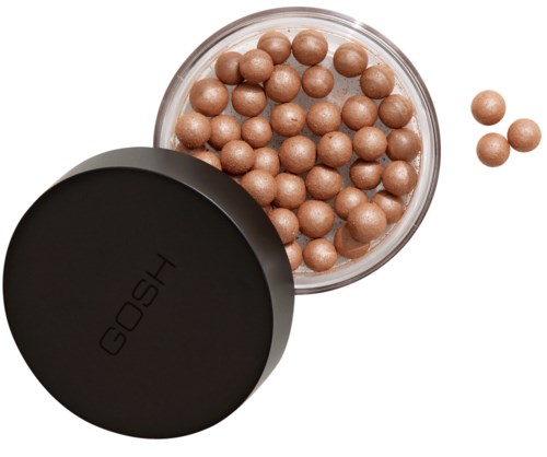 Een ronde container met een zwarte deksel met het label "GOSH" bevat beige make-up parels. Sommige parels liggen buiten de container.