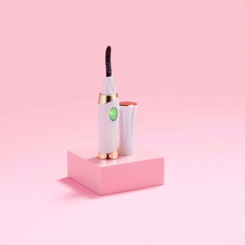 Een roze en witte gadget met een groene knop staat op een roze blok, met één uiteinde dat rookt.