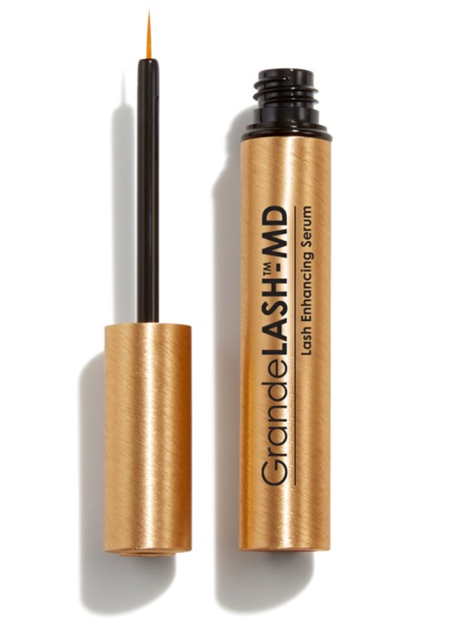 Een gouden buisje met wimperserum en een borstel ernaast, gebruikt voor wimperverlenging.