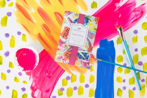 Colorful abstract background with paintbrushes, a notebook, and painted dots and strokes.