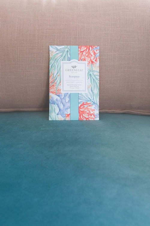 A colorful card with leaf and coral patterns stands against a beige background on a teal surface.