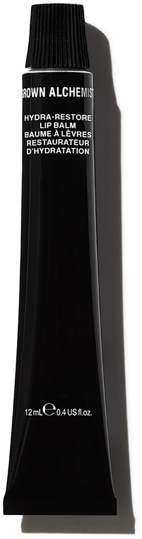 Een zwarte tube van BROWN ALCHEMY lippenbalsem met label 'HYDRA-RESTORE' en zwarte dop.