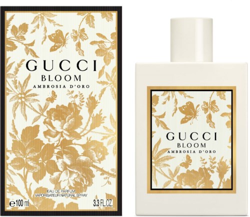 Een parfumfles en doos met gouden bloemendessin en zwarte randen. De fles is wit met hetzelfde etiket.