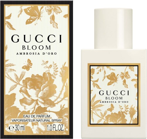 Een witte parfumefles met een gouden bloemenpatroon, naast een doos met hetzelfde patroon.