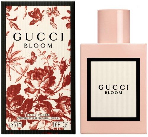 Een roze parfumfles en doos met bloem- en vlinderillustraties, allebei gelabeld GUCCI BLOOM.