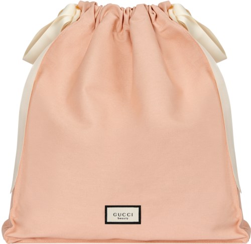 A peach-colored bag with white ribbon sides and a Gucci beauty label at the bottom.