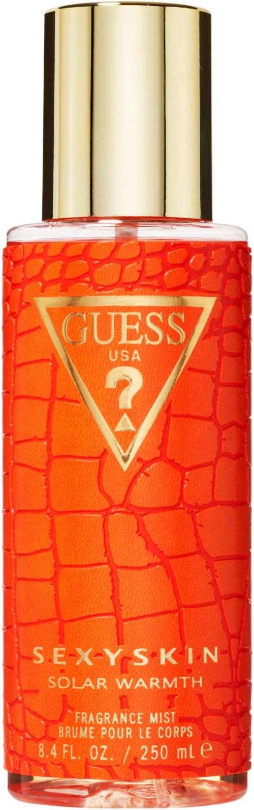 Een Guess geurspray fles met een gouden dop, oranje gebarsten patroon en label met "Guess USA" en "Sexy Skin".