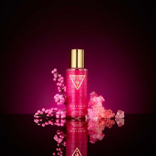 Roze fles met gouden dop, omgeven door roze bessen en ijsstructuren, op een donkere achtergrond.