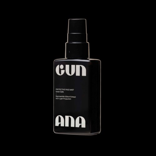 Een zwarte sprayfles met labels "GUN" en "ANA," met details over ingrediënten en bescherming van gezichtsspray.