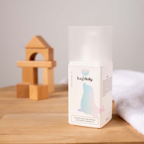 A box of body and hair gel with a bear illustration, placed on a wooden surface near a towel and wooden blocks.