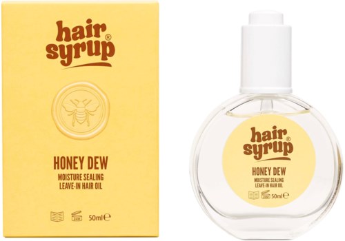 A clear round bottle and yellow box of Honey Dew hair oil with a bee logo and text.
