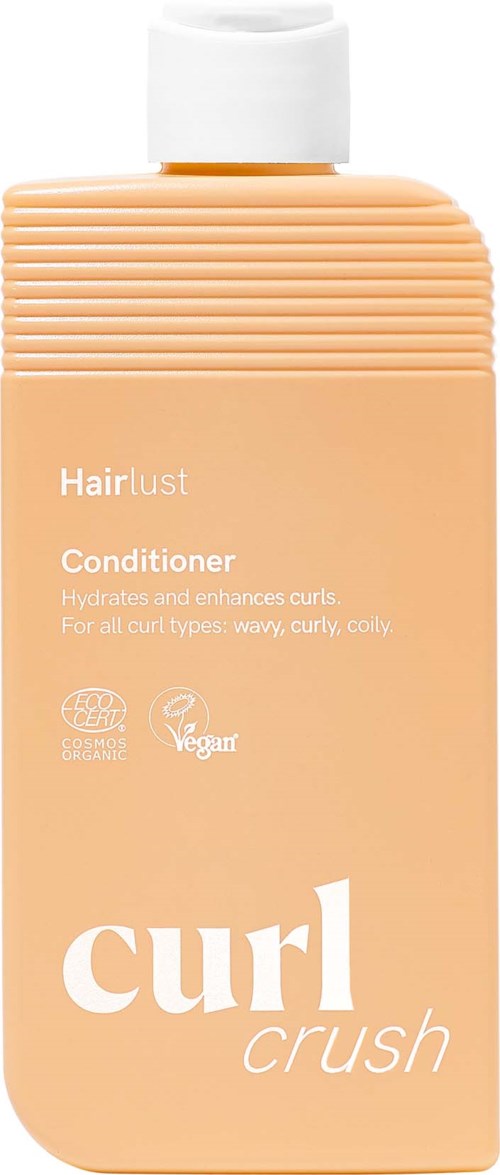 Ferskapelefarget flaske med Hairlust curl crush balsam med hvit lokk og teksturert topp, merket for fuktighet og forbedring av krøller.