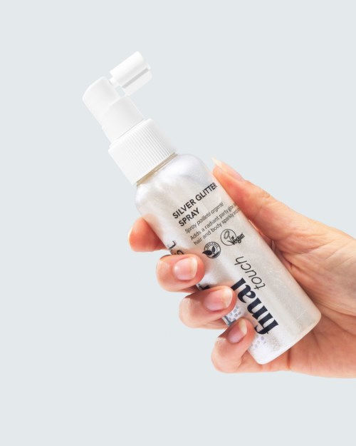 A hand holding a small spray bottle labeled Silver Glitter Spray for makeup or craft use.