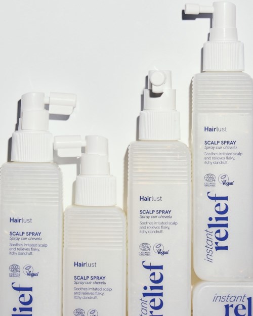 Fyra vita flaskor med Hairlust hårbottenpray med sprayhuvuden, märkta som lindrande och lugnande.