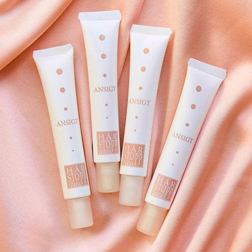 Four white tubes labeled 'ANSIGT' and 'HÅRSTOPP' are on a pink satin background.