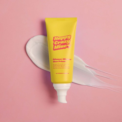 Gele tube met 'Happy Crazy Mine' en witte crème op roze achtergrond.