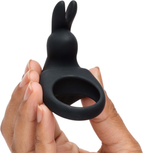 A black, rabbit-shaped silicone object with a ring at the bottom, held by a person's hand.