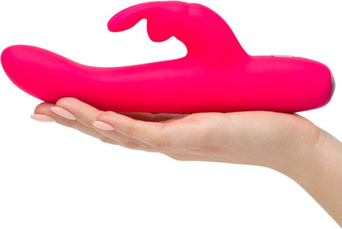 En hand håller ett stort rosa silikonföremål format som en val. Föremålet är slätt och kurvigt.