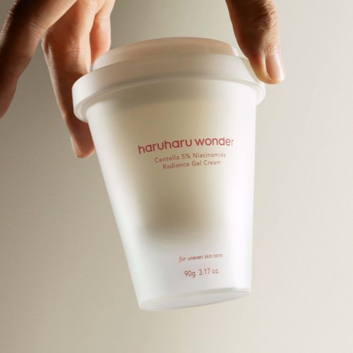 A person's hand holds a white jar labeled 'haruharu wonder' with text about skincare ingredients and weight.
