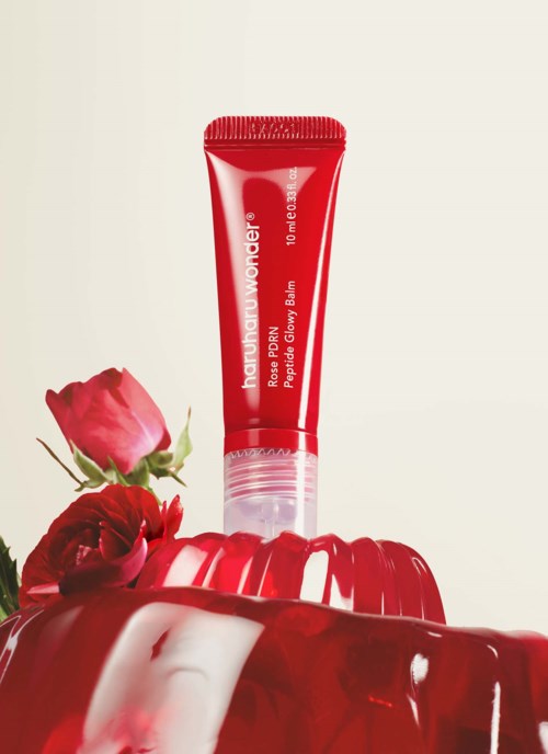 Red tube of lip balm with roses and a glossy red container nearby.
