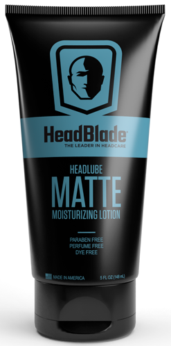 Musta putkilopussi, jossa on sininen tarra ja pää-kuvake, sekä tuotteen nimi HeadBlade Matte, kosteusemulsio pään iholle.
