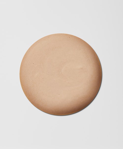 Pyöreä, beige, sileä kiekko valkoisella taustalla.