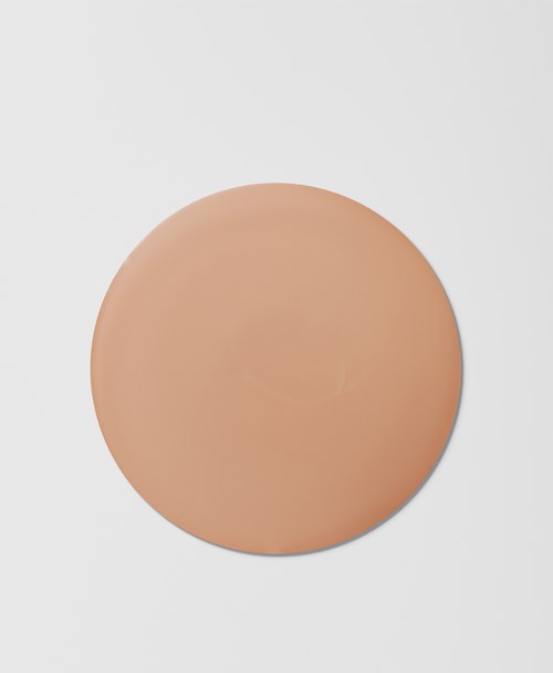 Pyöreä, beige meikkikynämaalituubi, jossa tasainen pinta harmaalla taustalla.