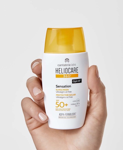 Käsi, joka pitää valkoista ja keltaista aurinkovoidepulloa, jossa on SPF 50+ -aurinkosuoja ja merkintä.