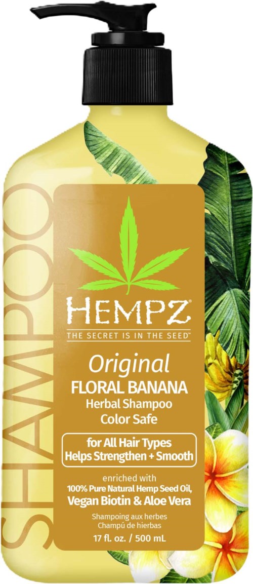 A shampoo bottle with a yellow label, green leaves, and floral designs, promoting natural ingredients and hair health.