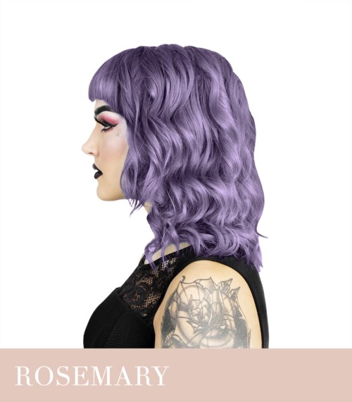 A woman with purple wavy hair, black lipstick, makeup, and a tattoo on her arm, wearing a black top.