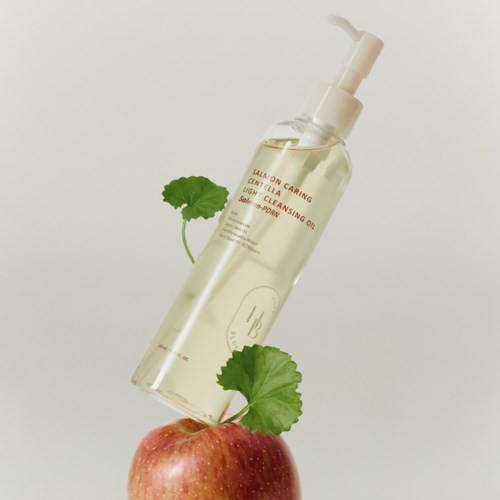 Eine klare Flasche mit Pumpaufsatz steht auf einem Apfel mit grünen Blättern vor einfachem Hintergrund.