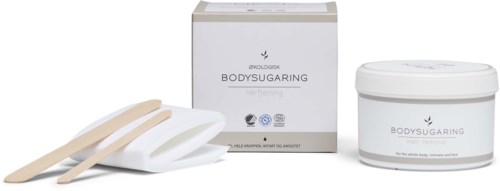Ein body shaping Kit besteht aus einer Schachtel, einem Glas und zwei Spatel für Hautpflege. Die Produkte sind in weißen Behältern.