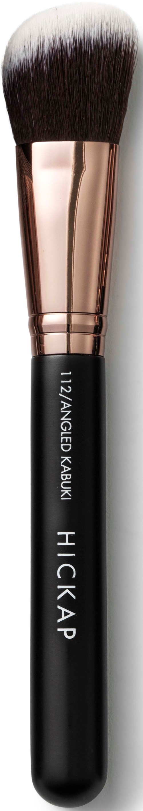 A makeup brush with black handle, rose gold ferrule, and soft bristles. Text on handle: "12/RAINBOW FAUX," "HICKAP."