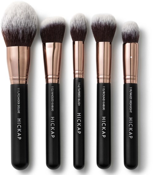 Set of five makeup brushes with black handles and rose gold ferrules, varying in size and shape.