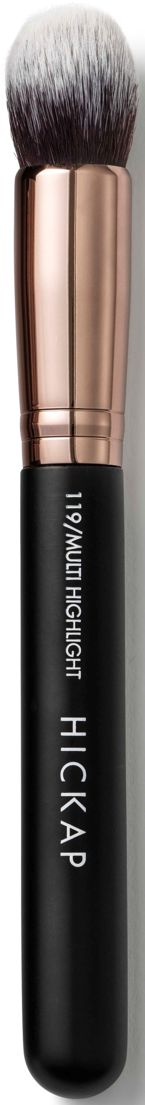 A makeup brush with a black handle and a rose gold ferrule, fluffy white and gray bristles.