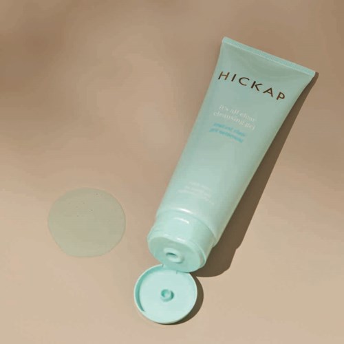 A light blue tube of skincare product with an open cap, labeled 'HICKAP', on a beige surface.