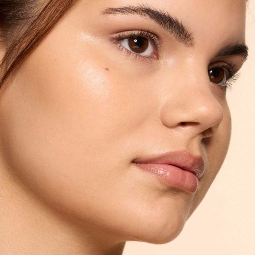 Close-up of a woman's face showing clear skin, brown eyes, and natural lips.
