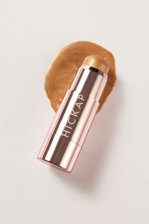 A lipstick tube with the word HICKAP on it and a beige lipstick shade. It is placed on a peach-colored makeup sponge.